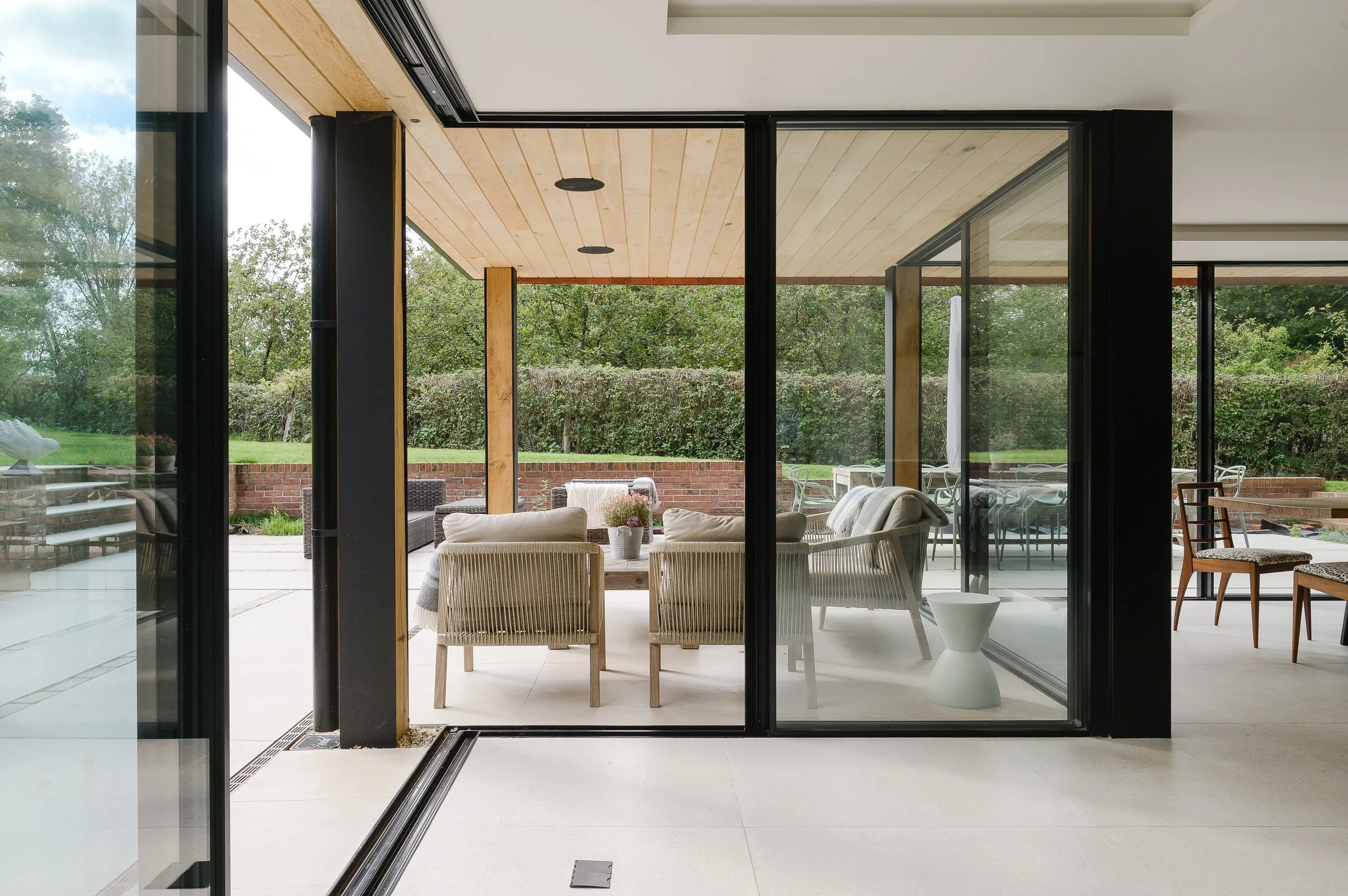 Sliding doors opening from the open-plan living space to an oak-lined loggia and garden, country house, Lodsworth