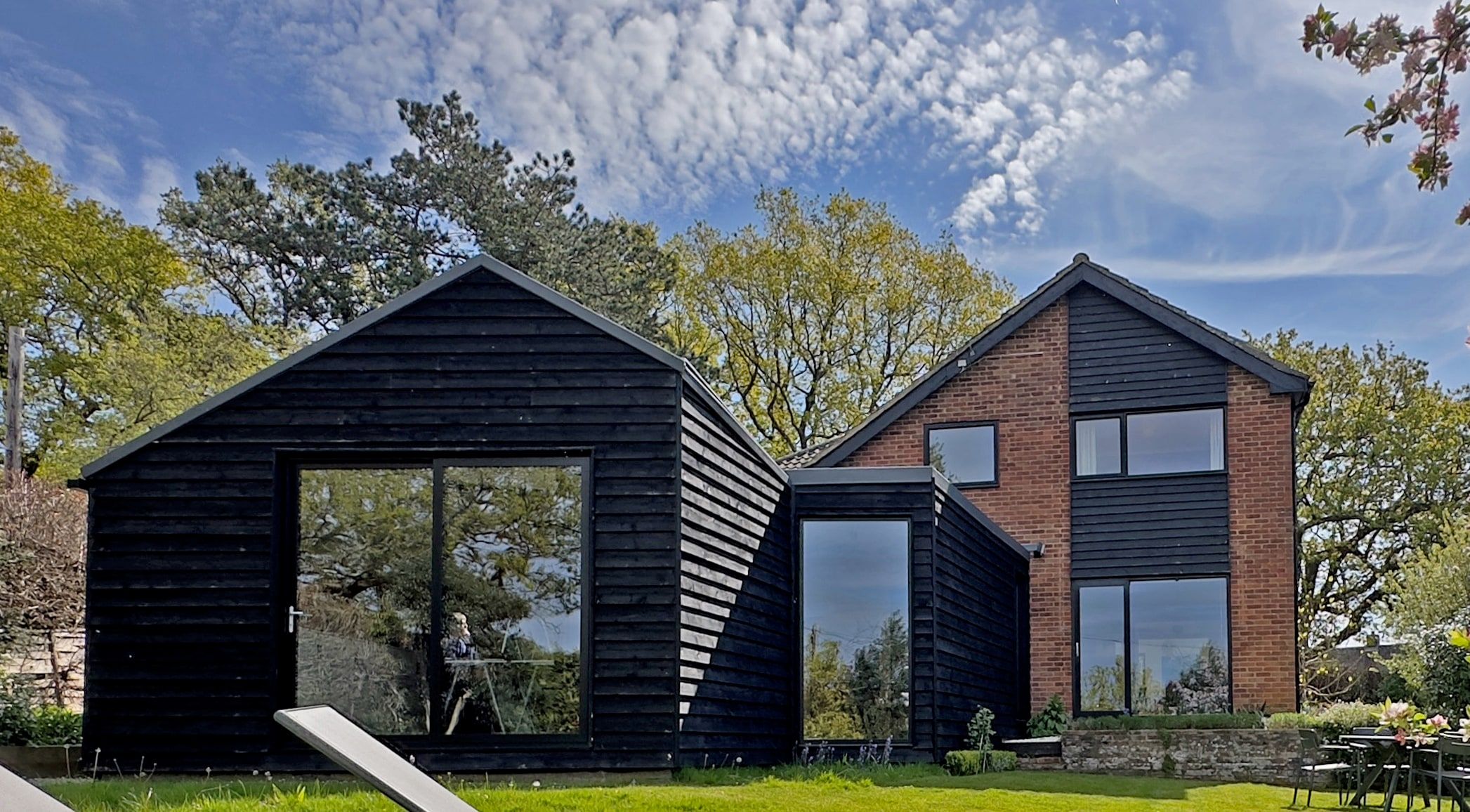Stained black timber garden room and picture window beside the brick house, 1960s house, Fernhurst.
