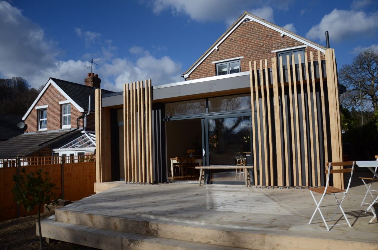 The cedar-clad single-storey rear extension seen from the garden beside the original house, period house, Haslemere.