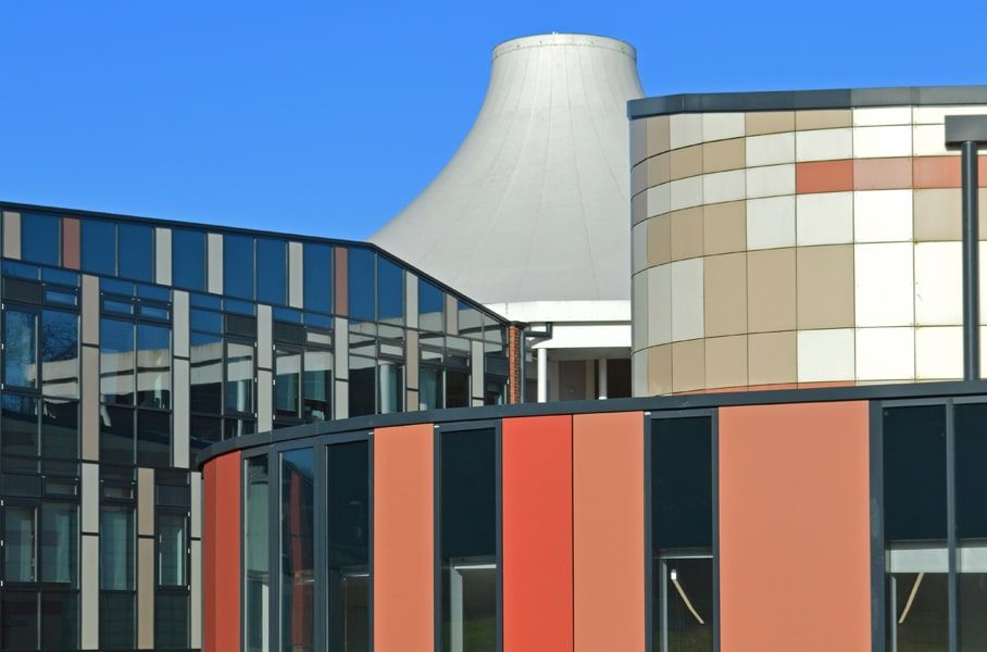 Curved facade of photovoltaic glazing and terracotta panels beside the existing school, St Bartholomew's School, Newbury.