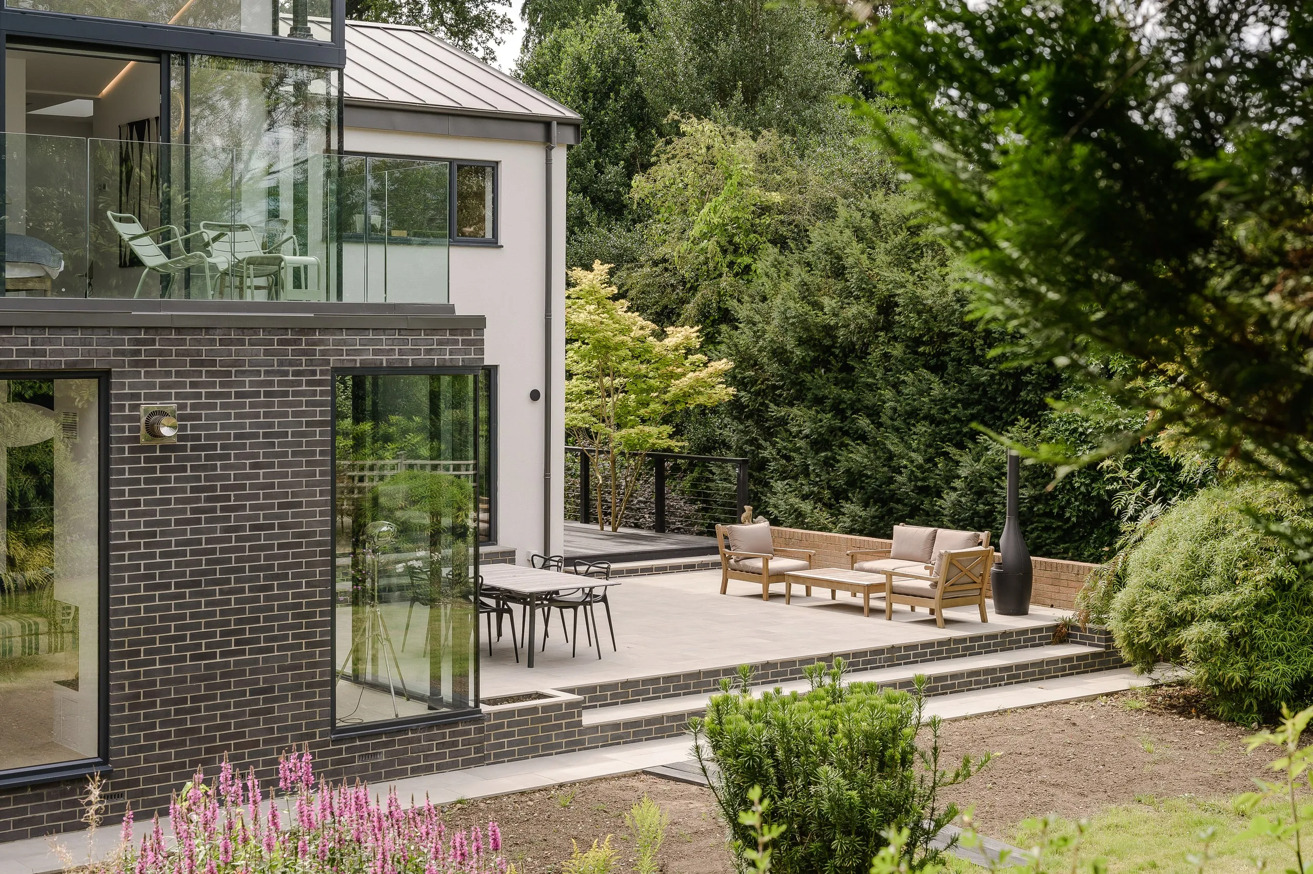 Brick and rendered elevations above a paved terrace, with steps down to the planted garden, 1960s house, Haslemere