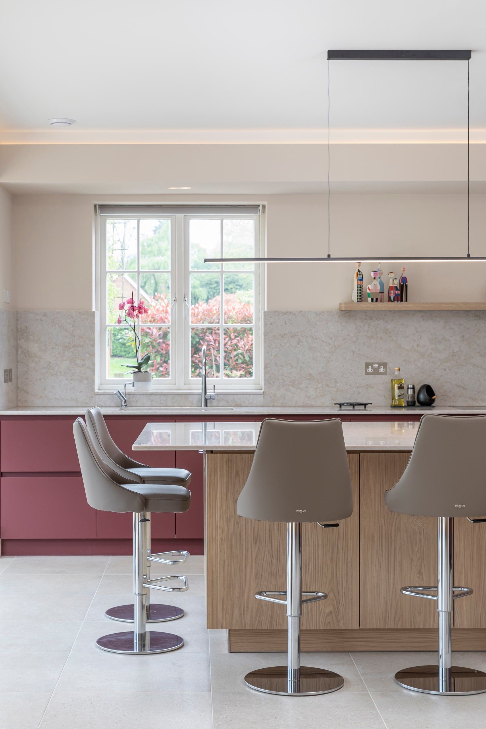 Kitchen sink and breakfast stools below a window looking to the garden, detached house, Shackleford.