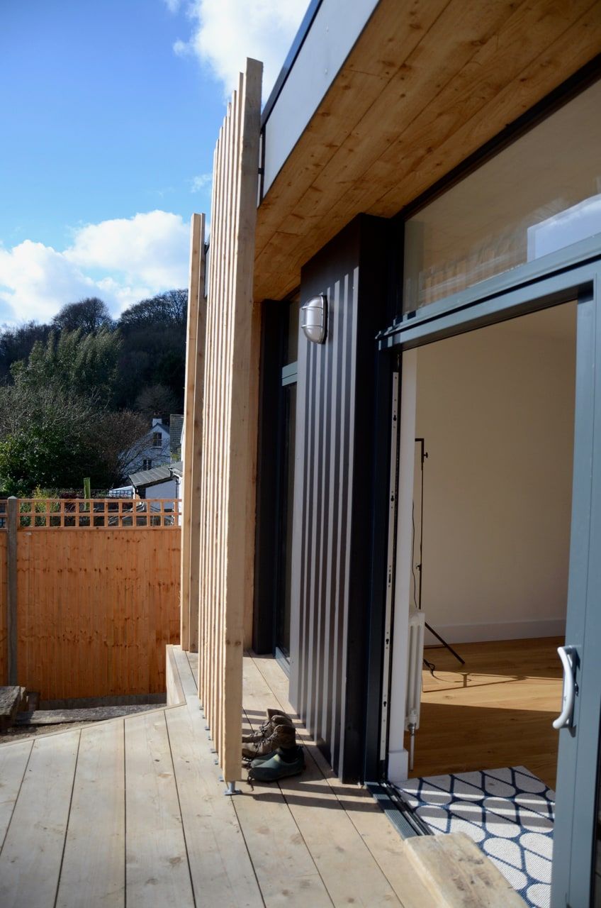 Vertical cedar louvres beside the open sliding door at the corner of the extension, period house, Haslemere.