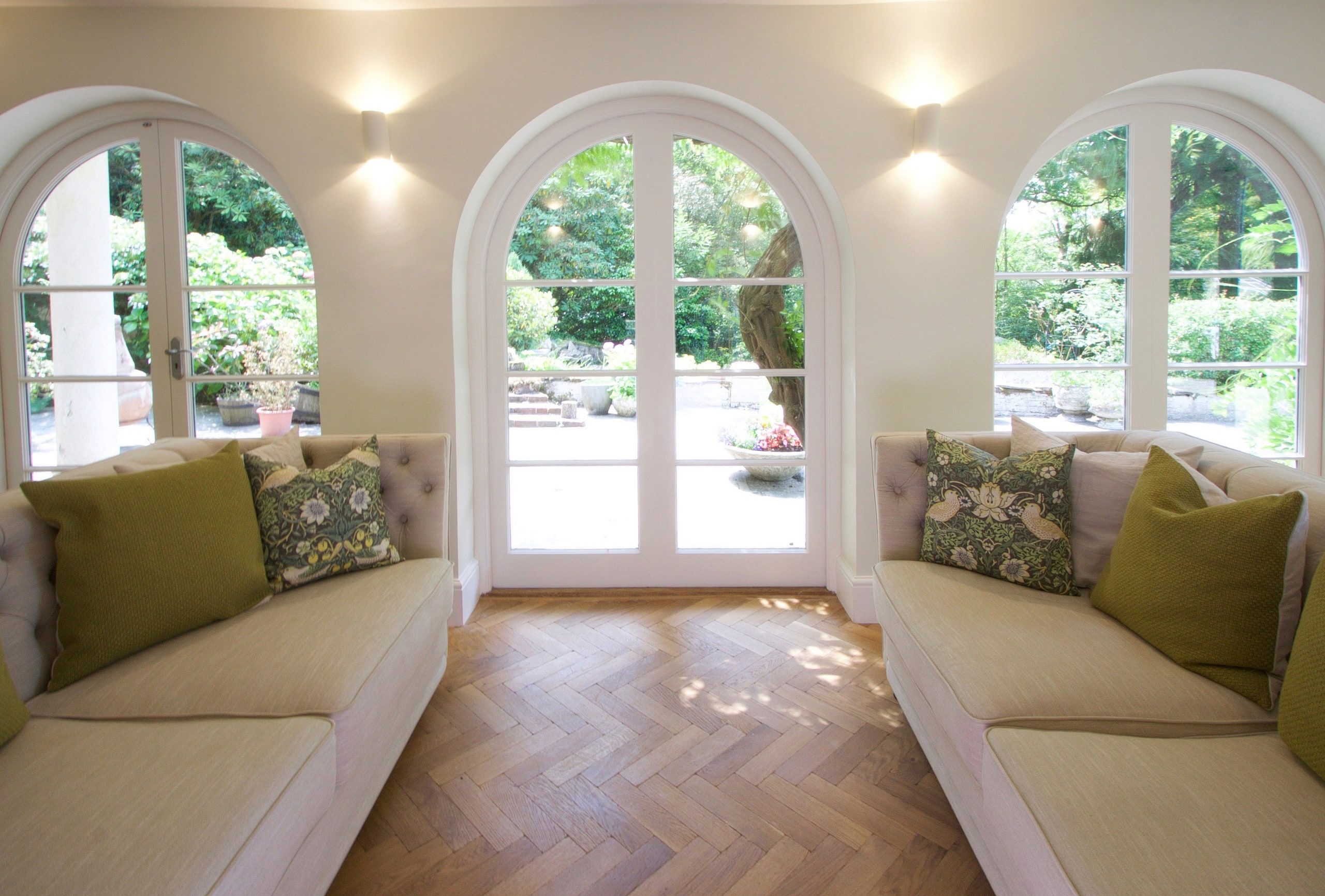 Window seats flanking the arched garden doors in the sitting room, 1930s country house, Mole Valley.