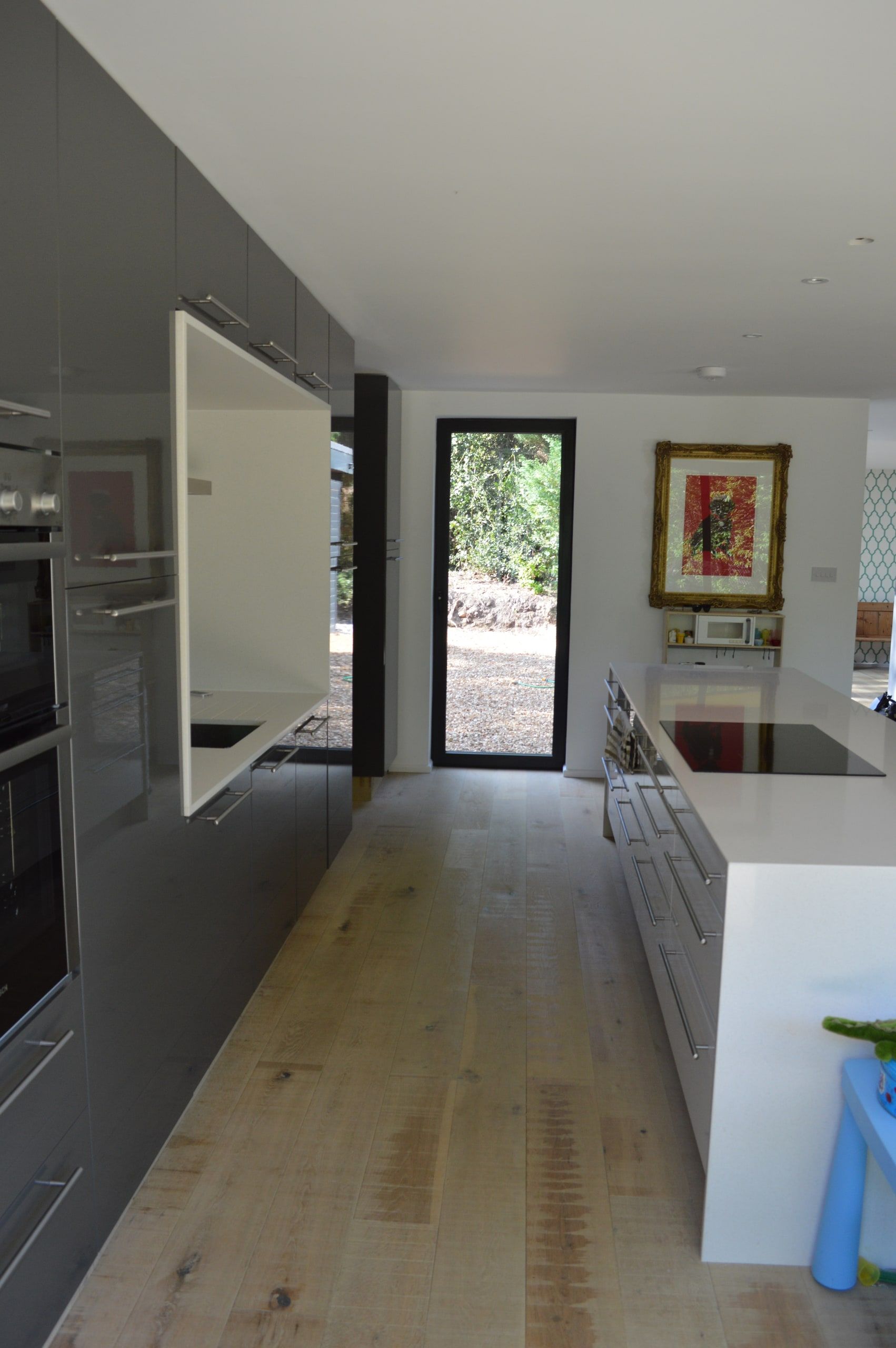 View along the kitchen to a full-height glazed door onto the garden, 1960s house, Haslemere.