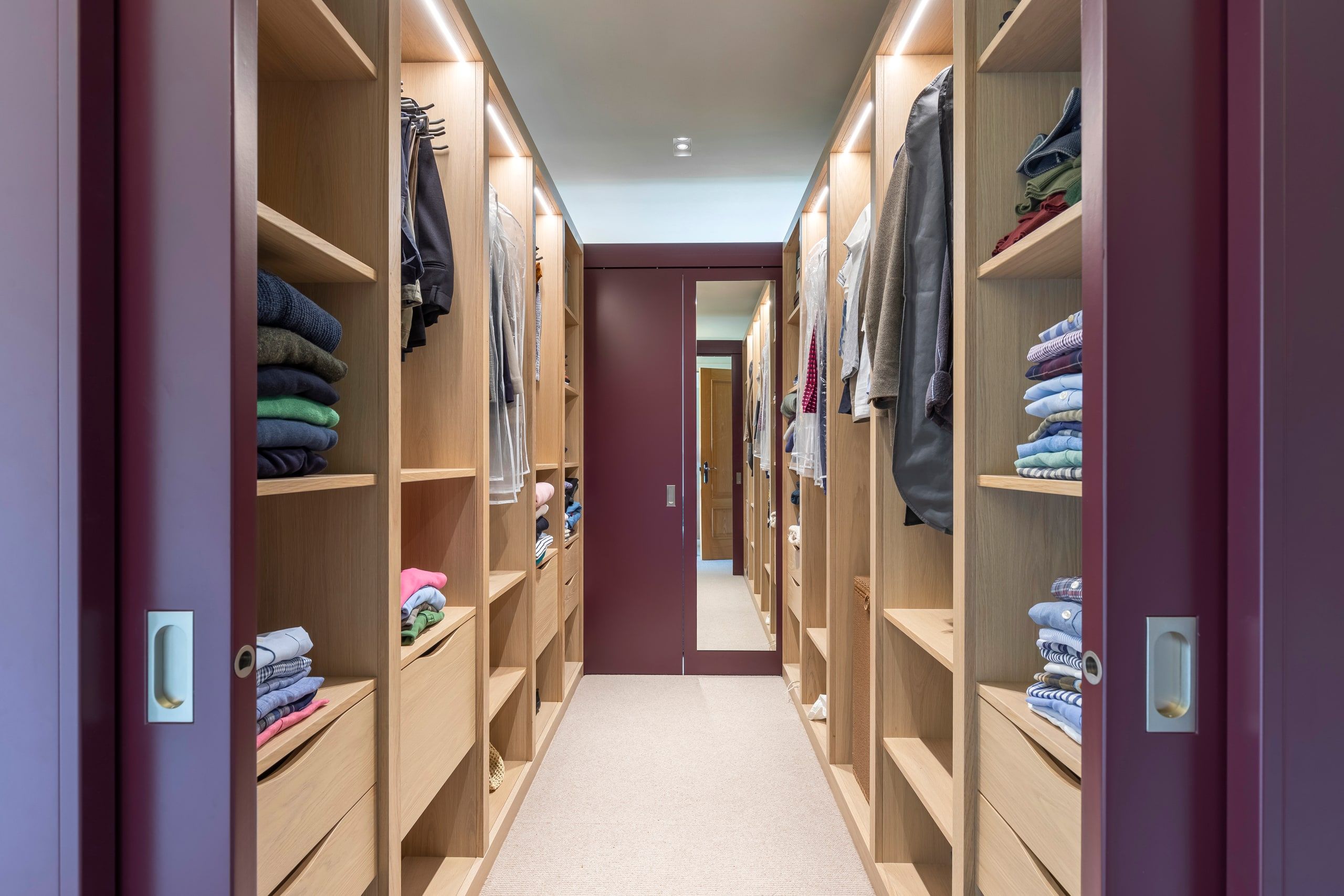 Bespoke dressing area lined with oak shelving between sliding doors, detached house, Shackleford.