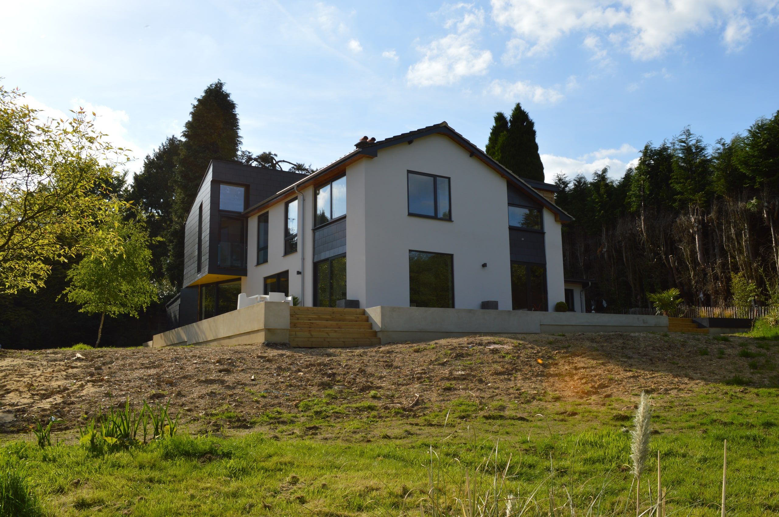 The rendered house and its slate-clad extension seen from the garden below, 1960s house, Haslemere.