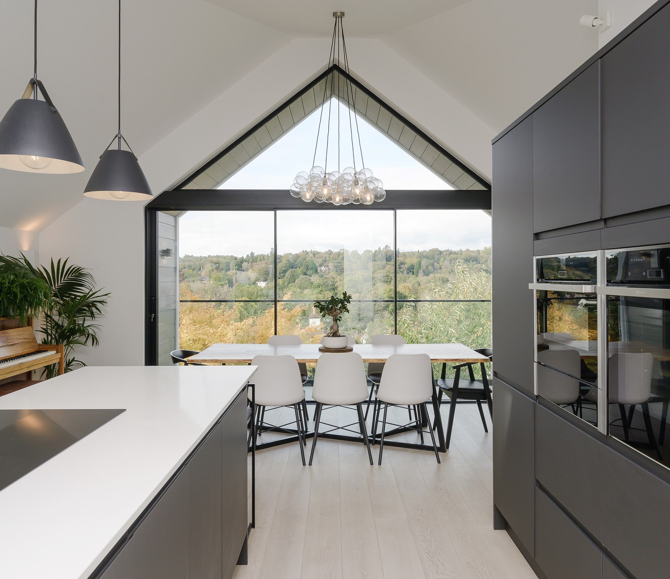 Open-plan kitchen and dining room under the full-height gable glazing, upside down house, Haslemere.