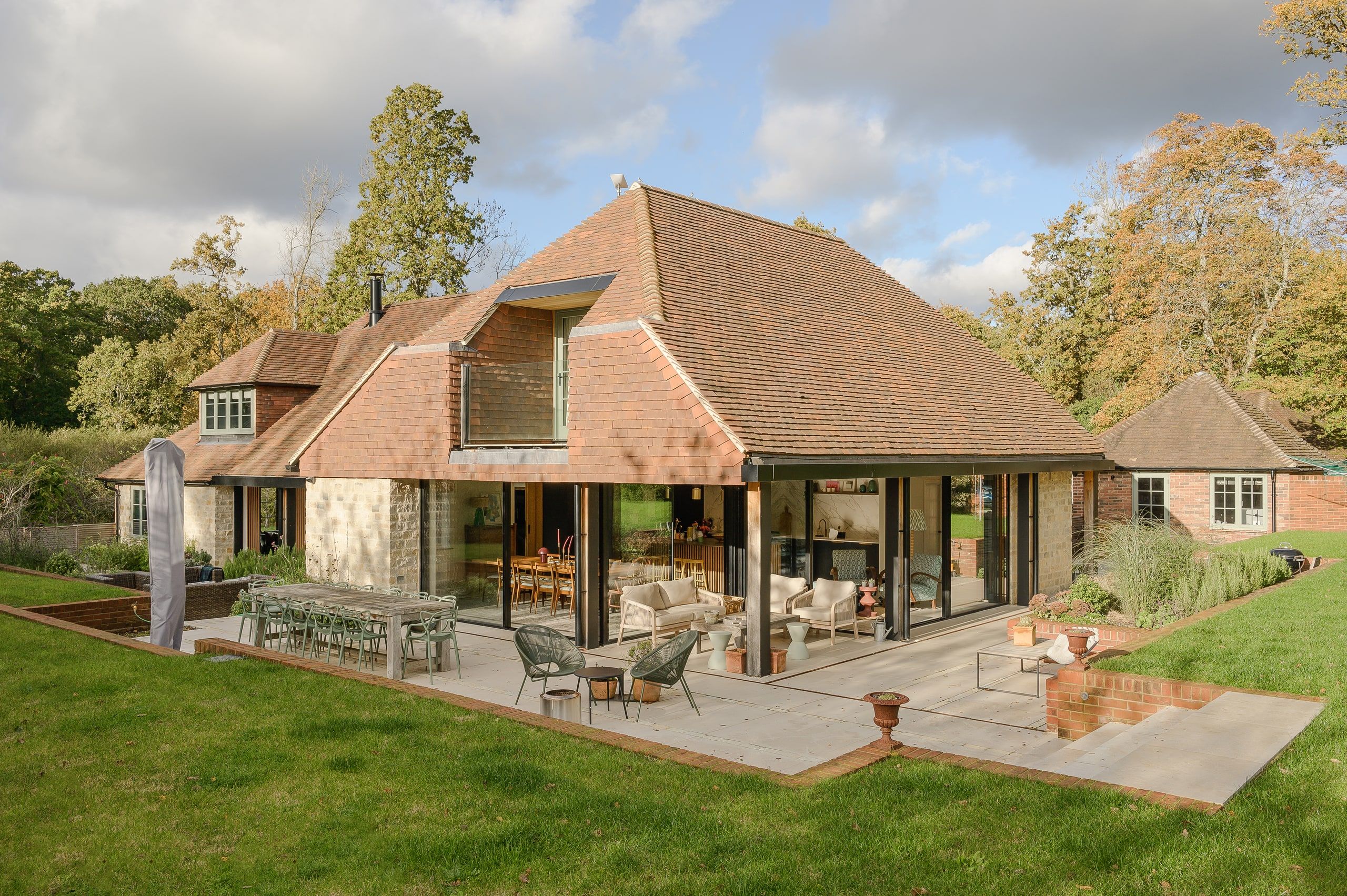 Deep clay-tiled roof over an open loggia and glazed doors onto the terrace, country house, Lodsworth