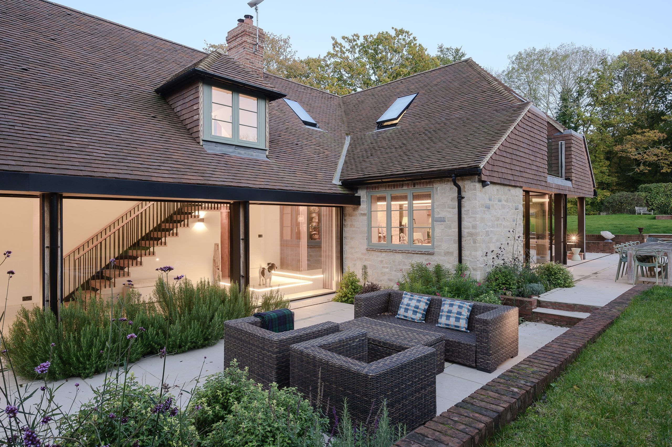 Evening light on the garden front, the staircase visible through full-height glazing, country house, Lodsworth