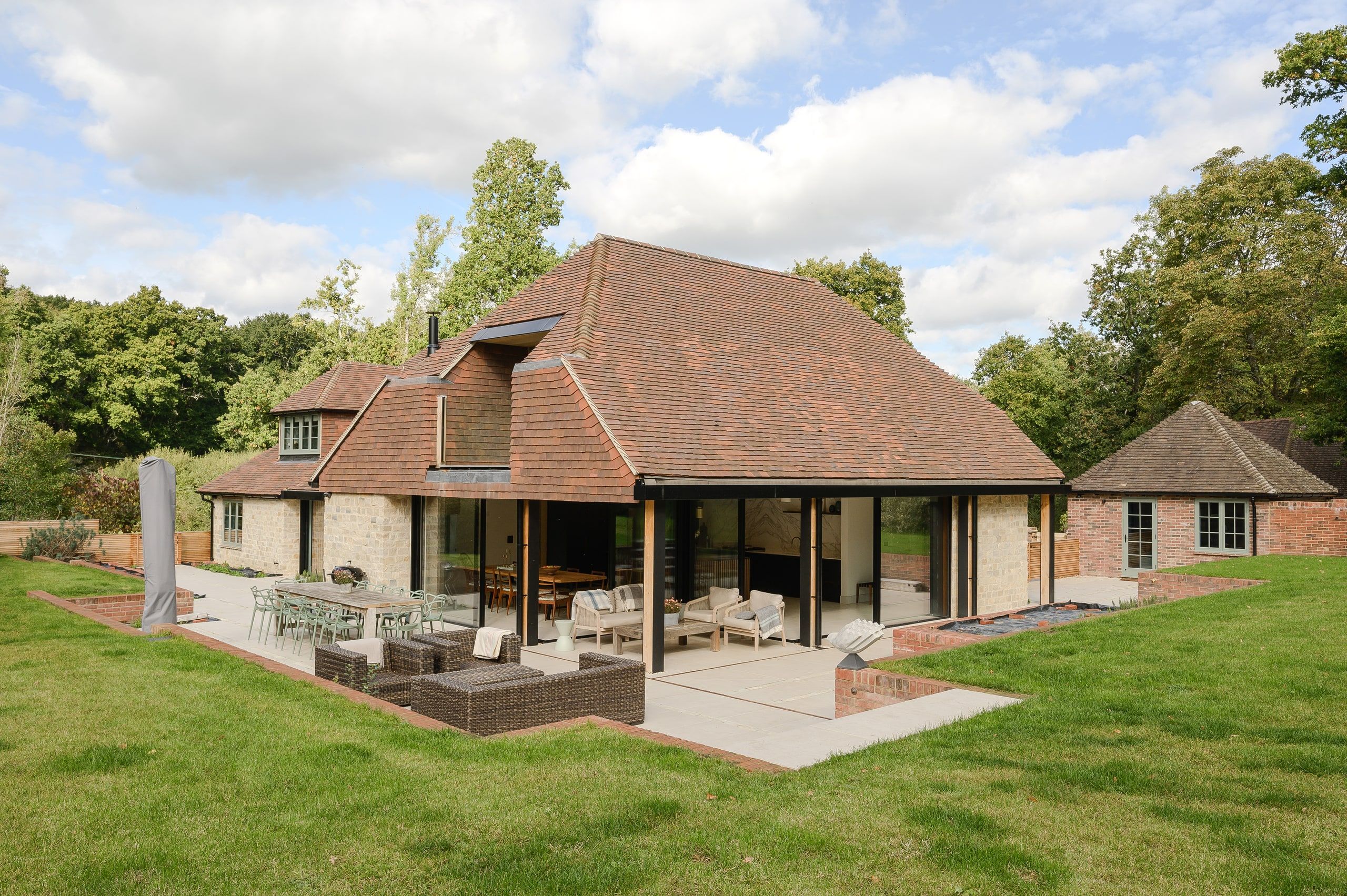 Garden elevation and loggia in daylight, with terrace seating on the sloping lawn, country house, Lodsworth